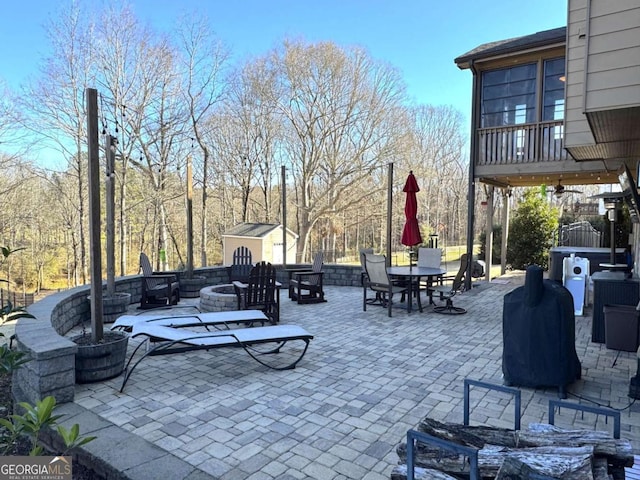 view of patio with an outdoor fire pit and a shed