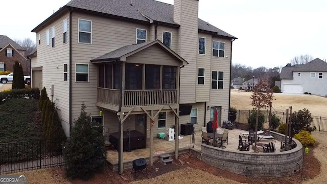 back of house with an outdoor fire pit, a sunroom, and a patio