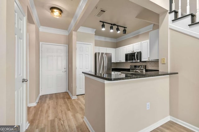 kitchen with appliances with stainless steel finishes, crown molding, white cabinets, and kitchen peninsula