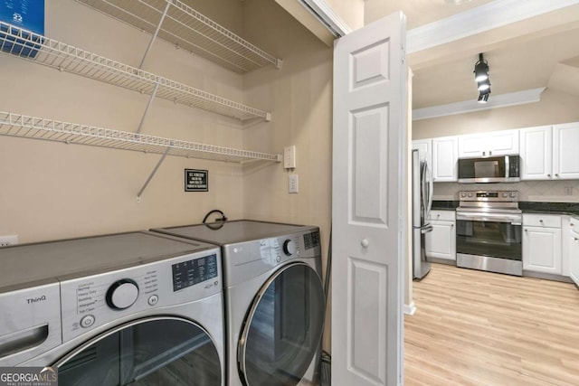 clothes washing area with light hardwood / wood-style floors and washer and clothes dryer