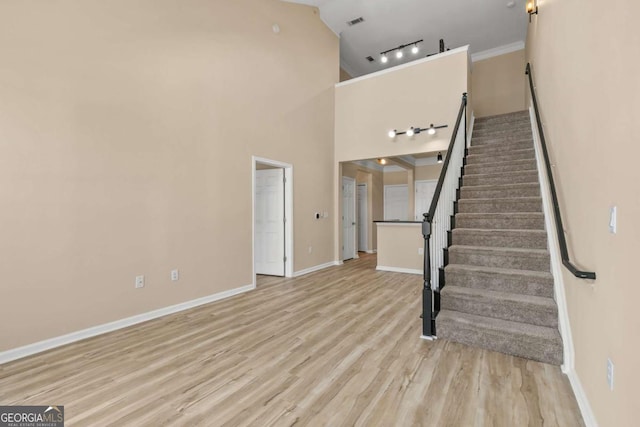 stairs with wood-type flooring and crown molding