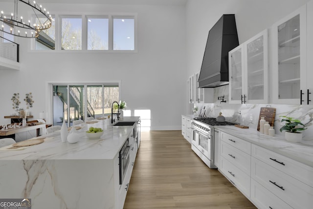 kitchen featuring pendant lighting, white cabinets, sink, double oven range, and custom range hood