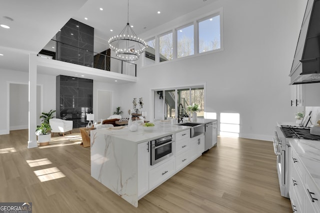 kitchen featuring stainless steel appliances, a high ceiling, light stone countertops, white cabinets, and sink