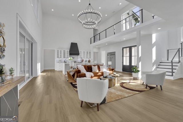 living room featuring light wood-type flooring, a high ceiling, and a notable chandelier