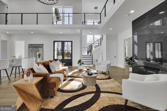 living room featuring a towering ceiling, light hardwood / wood-style floors, and french doors