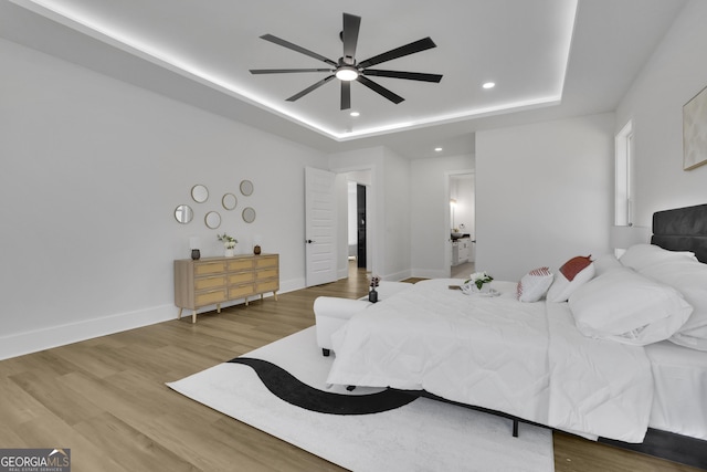 bedroom with ceiling fan, hardwood / wood-style floors, and a tray ceiling