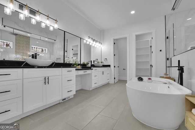 bathroom with tile patterned flooring, a bath, vanity, and tasteful backsplash