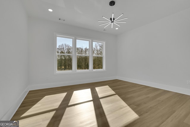 empty room featuring an inviting chandelier and hardwood / wood-style floors