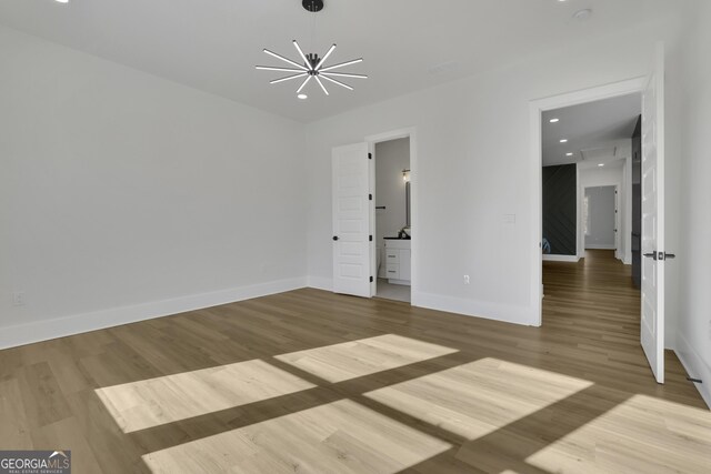 unfurnished room with an inviting chandelier and wood-type flooring