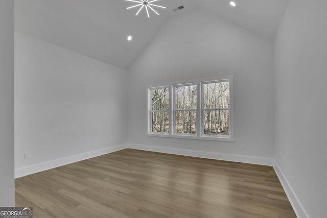 unfurnished room with hardwood / wood-style floors and high vaulted ceiling