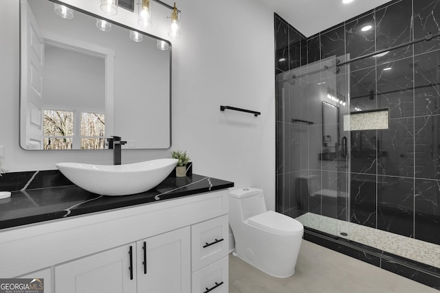 bathroom featuring toilet, tile patterned flooring, a tile shower, and vanity