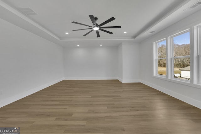 spare room featuring ceiling fan, light hardwood / wood-style flooring, and a tray ceiling