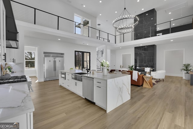 kitchen featuring stainless steel appliances, white cabinetry, a towering ceiling, and light stone countertops