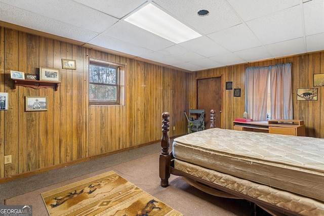 carpeted bedroom featuring a paneled ceiling and wooden walls