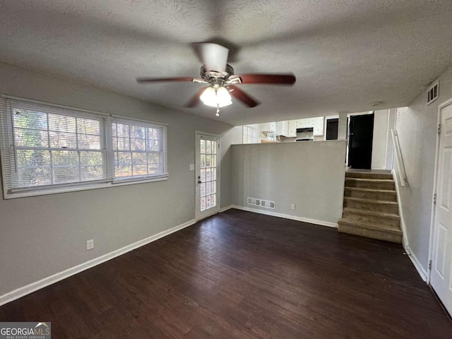 spare room featuring a textured ceiling, ceiling fan, a wealth of natural light, and dark hardwood / wood-style flooring