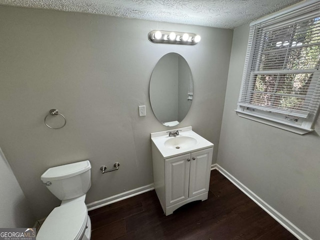 bathroom with a textured ceiling, toilet, vanity, and hardwood / wood-style floors