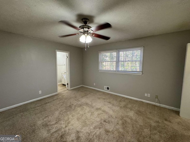 unfurnished bedroom with ceiling fan, light colored carpet, ensuite bathroom, and a textured ceiling