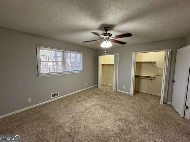 unfurnished bedroom featuring ceiling fan, light colored carpet, a spacious closet, a textured ceiling, and a closet