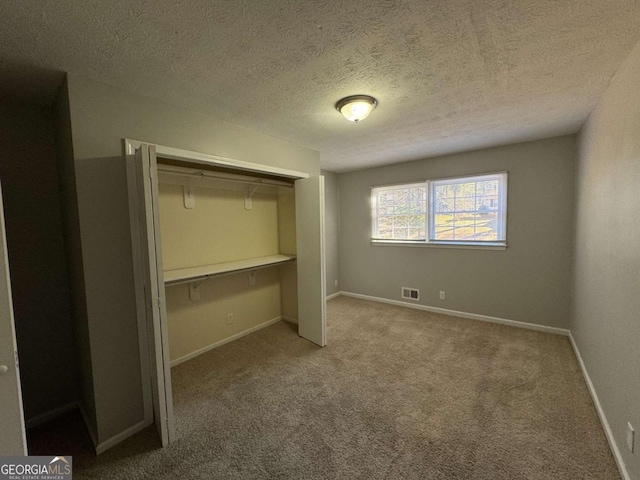 unfurnished bedroom with a textured ceiling, a closet, and carpet flooring