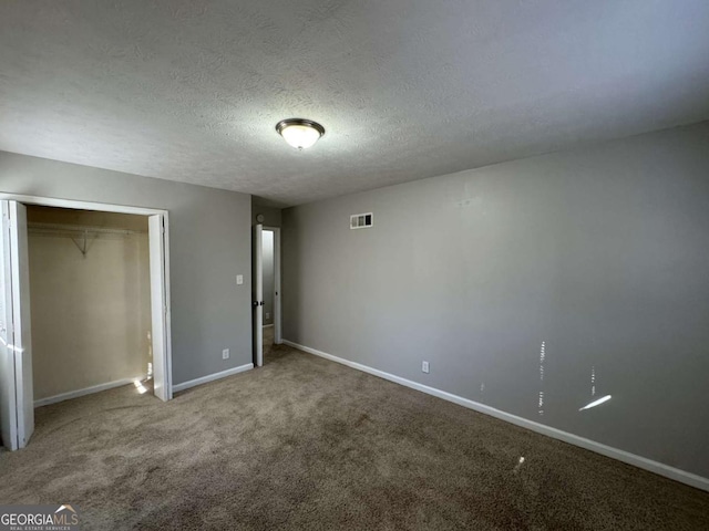 unfurnished bedroom with a textured ceiling, a closet, and carpet flooring