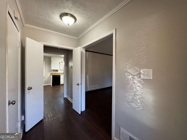 corridor featuring a textured ceiling, dark wood-type flooring, and ornamental molding