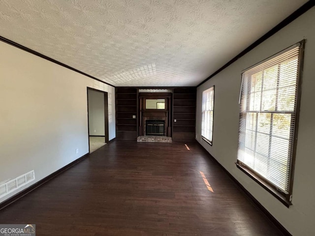 unfurnished living room featuring a textured ceiling, a brick fireplace, crown molding, and dark hardwood / wood-style floors