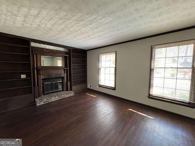 unfurnished living room featuring built in shelves, a fireplace, plenty of natural light, and crown molding