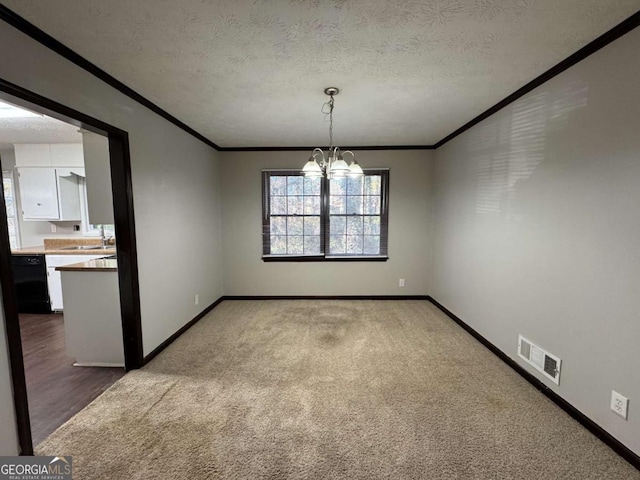 unfurnished dining area with carpet floors, a notable chandelier, a textured ceiling, and ornamental molding