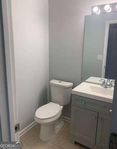 bathroom with toilet, vanity, and tile patterned flooring