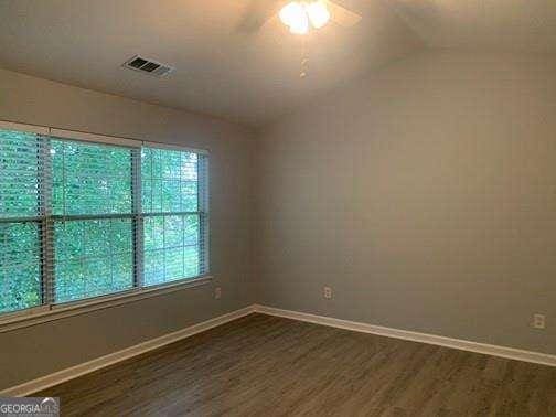 empty room with lofted ceiling, ceiling fan, and dark hardwood / wood-style floors