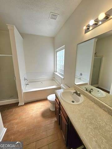 full bathroom with toilet, vanity, a textured ceiling, and shower with separate bathtub