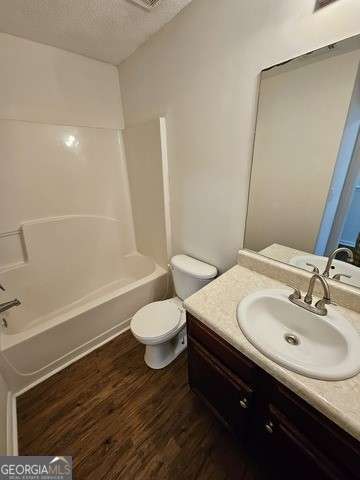 full bathroom featuring tub / shower combination, a textured ceiling, vanity, toilet, and hardwood / wood-style flooring