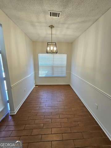 unfurnished dining area with dark hardwood / wood-style flooring and a notable chandelier