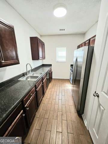 kitchen featuring dark brown cabinets, stainless steel fridge, and sink