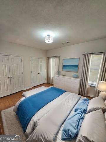 bedroom featuring two closets, hardwood / wood-style floors, and multiple windows