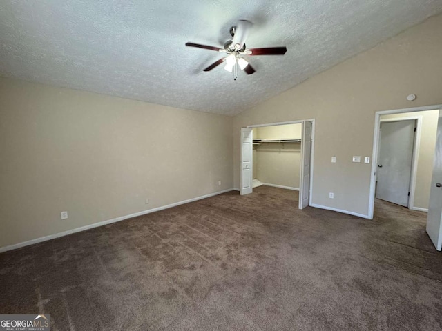 unfurnished bedroom featuring ceiling fan, dark colored carpet, a closet, lofted ceiling, and a textured ceiling