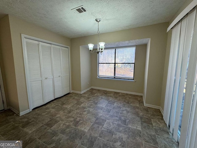 unfurnished bedroom with a textured ceiling, a closet, and an inviting chandelier