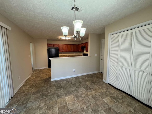 kitchen with a textured ceiling, hanging light fixtures, black fridge, kitchen peninsula, and a notable chandelier