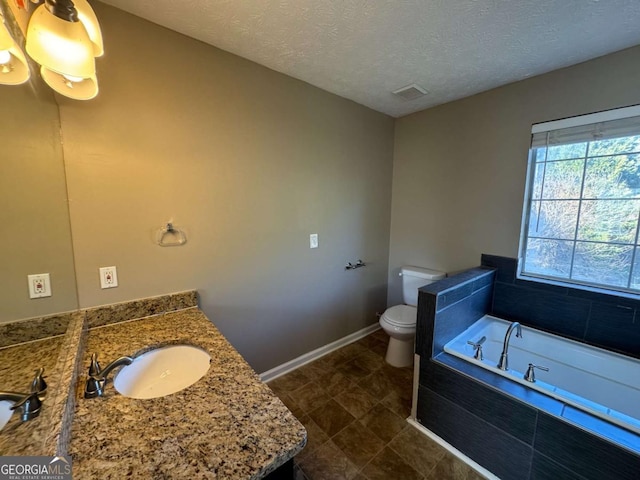 bathroom featuring a textured ceiling, a bathing tub, toilet, and vanity