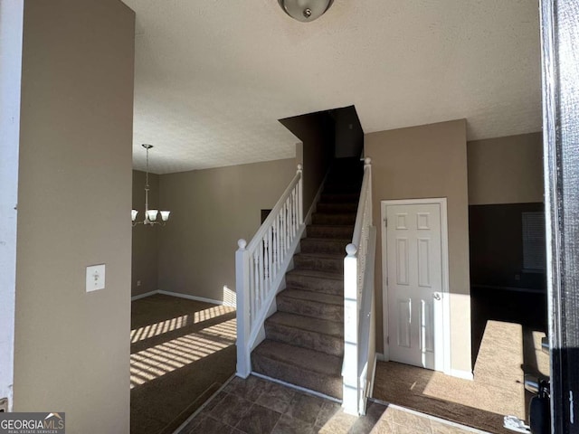 staircase featuring an inviting chandelier and a textured ceiling