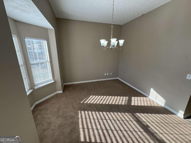 unfurnished room featuring a textured ceiling, a notable chandelier, and dark colored carpet