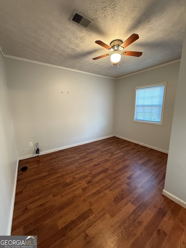 spare room featuring ceiling fan, dark wood-type flooring, a textured ceiling, and ornamental molding