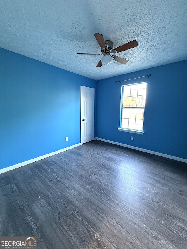 spare room featuring a textured ceiling, dark wood-type flooring, and ceiling fan