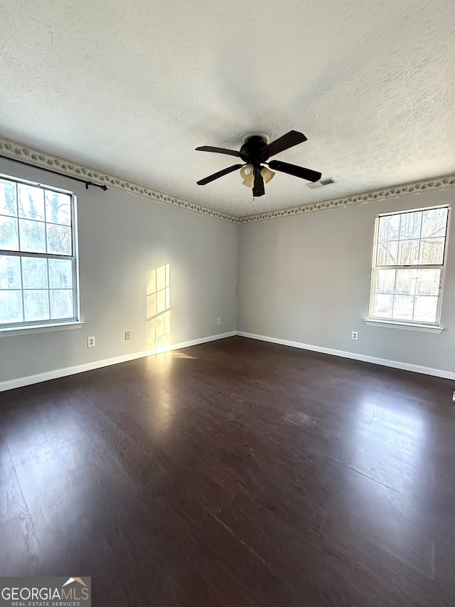 spare room with ceiling fan, dark wood-type flooring, a textured ceiling, and plenty of natural light