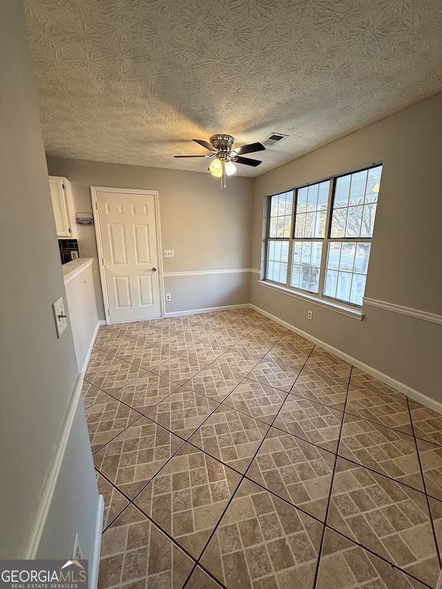 empty room featuring a textured ceiling and ceiling fan