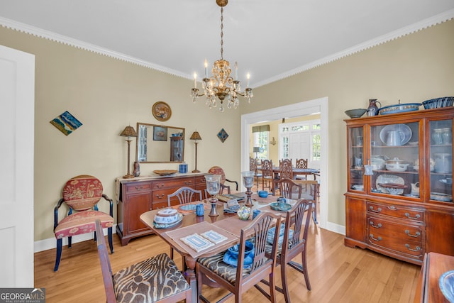 dining room with a notable chandelier, ornamental molding, and light hardwood / wood-style floors