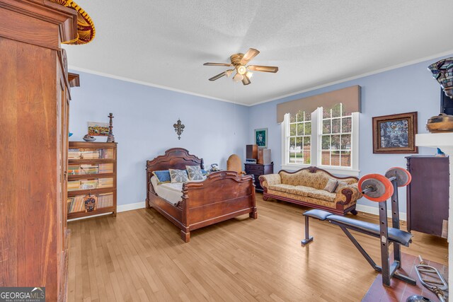 bedroom with ceiling fan, a textured ceiling, wood-type flooring, and ornamental molding