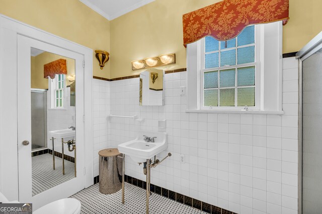 bathroom featuring tile walls, sink, an enclosed shower, and toilet