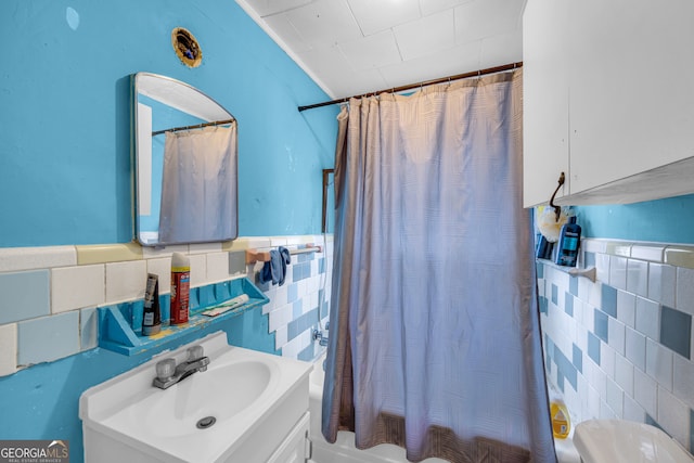 bathroom with shower / bathtub combination with curtain, tile walls, and vanity