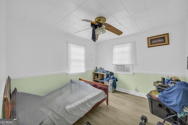 bedroom featuring cooling unit, light wood-type flooring, and ceiling fan